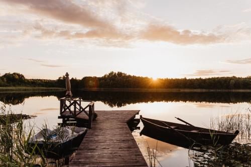 a dock with two boats on a lake at sunset at Beržų namelis - Birch cabin in Kučiūnai