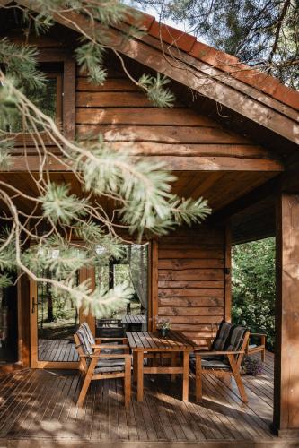 a wooden cabin with a table and chairs on a deck at Beržų namelis - Birch cabin in Kučiūnai