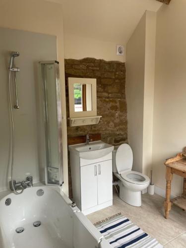 a bathroom with a white tub and a toilet at Beautiful countryside Byre conversion in Shrewsbury