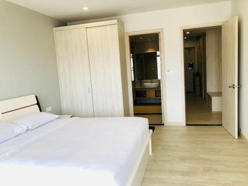 a bedroom with a white bed and a bathroom at Gold Coast Luxury Apartment Nha Trang in Nha Trang