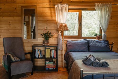 a bedroom with a bed and a chair and a window at Beržų namelis - Birch cabin in Kučiūnai