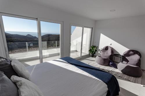 a bedroom with a large bed and large windows at Arrifana Sunset Sea View Villa in Praia da Arrifana