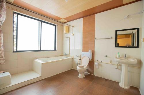 a bathroom with a tub and a toilet and a sink at GP Hotels and Resorts in Nashik