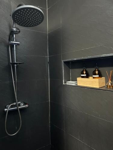 a shower in a black bathroom with a shower head at Charmant appartement avec terrasse, vue sur lagon in Mamoudzou