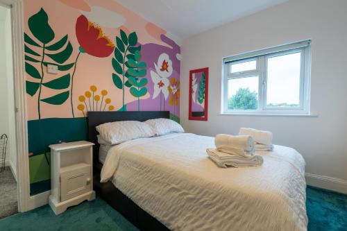 a bedroom with a bed and a wall with flowers at 3 bedroom home and garden in North Bristol in Bristol