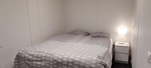 ein kleines Schlafzimmer mit einem Bett und einer Lampe in der Unterkunft Mökki Vanajaveden rannalla Kirstulan Kartanossa in Hämeenlinna