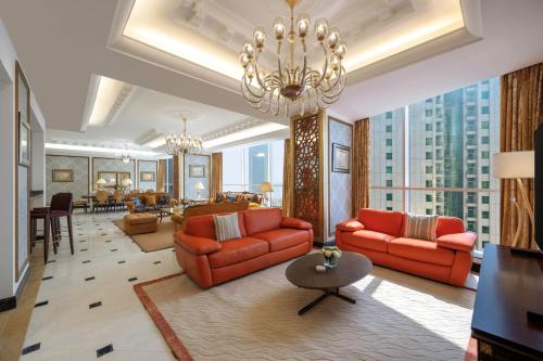 a living room with red furniture and a chandelier at Dusit Hotel & Suites - Doha in Doha