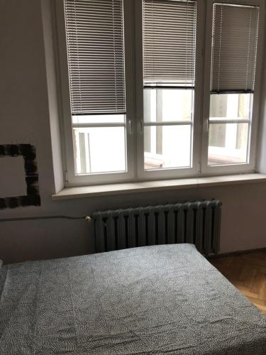 a bedroom with a bed and two windows with blinds at Pokój 12C in Krakow