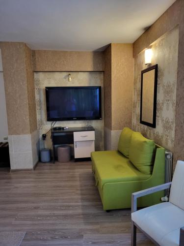 a living room with a green couch and a flat screen tv at Vida Family Hotel in Vidin