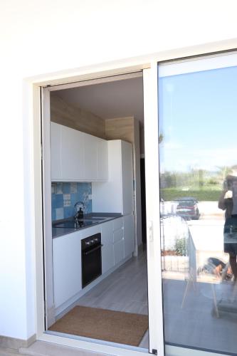 a kitchen with a sliding glass door leading to a balcony at Pescoluse Apartments in Marina di Pescoluse