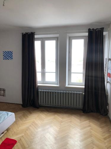 a bedroom with two windows and a wooden floor at Pokój 11A in Krakow