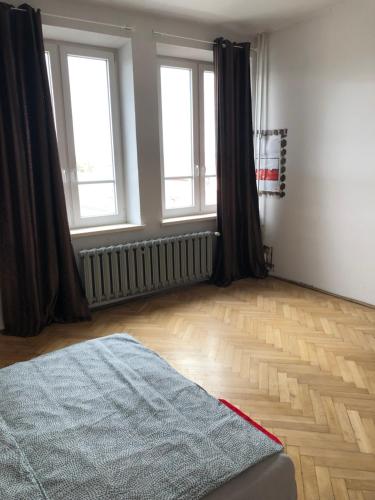 a bedroom with two windows and a wooden floor at Pokój 11A in Krakow