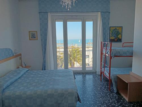 una camera con letto e un balcone con vista sull'oceano di Hotel Rosa Meublé a Porto San Giorgio