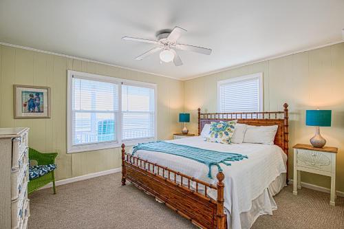 een slaapkamer met een houten bed en 2 ramen bij Albion Topsail Beach in Topsail Beach