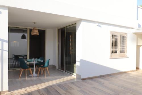 a room with a table and chairs on a balcony at Pescoluse Apartments in Marina di Pescoluse