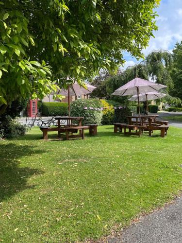 two picnic tables and an umbrella in a park at The Finch Hatton Arms in Sleaford
