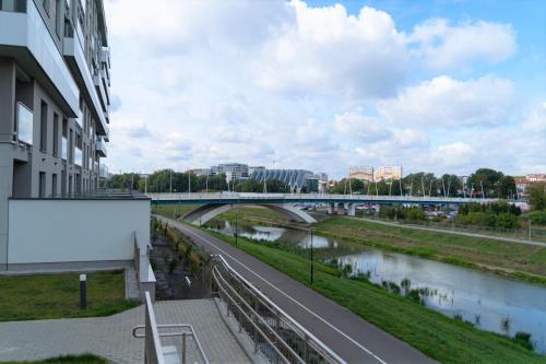 a bridge over a river next to a building at Capital Towers - Apartament Pop-art z widokiem na rzekę in Rzeszów
