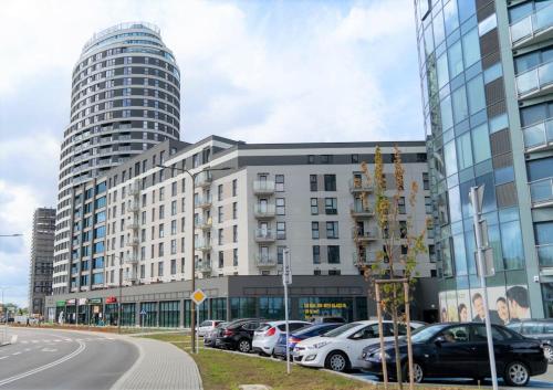 duży budynek z samochodami zaparkowanymi na parkingu w obiekcie Capital Towers - Apartament Pop-art z widokiem na rzekę w mieście Rzeszów