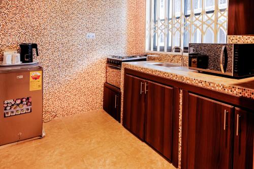 a kitchen with a sink and a microwave and a refrigerator at AIDEN HOMES AND APARTMENTS HOTEl in Koforidua