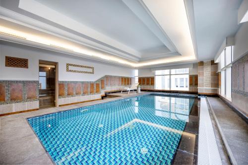ein großer Pool in einem großen Zimmer mit einer Decke in der Unterkunft Dusit Hotel & Suites - Doha in Doha