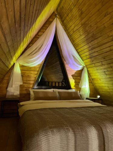 a bed in a wooden room with a window at Eco cottage Kazbegi in Kazbegi