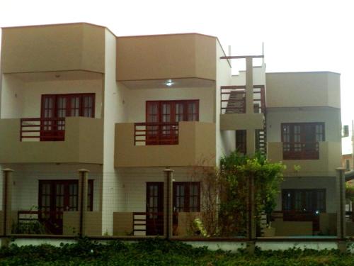 a large white building with red windows at Pousada Na Beira do Mar in Baía da Traição