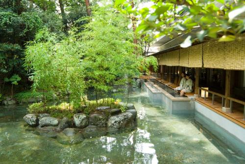 a person sitting on a bench next to a pond in front of a building at Shimobe Hotel in Minobu