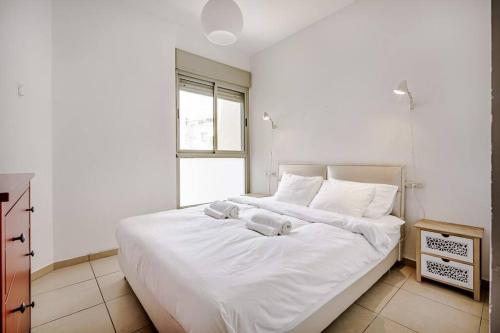 a bedroom with a large white bed with a window at Flea Market 1BR - 6 09 Tankhum St Tel Aviv # in Tel Aviv