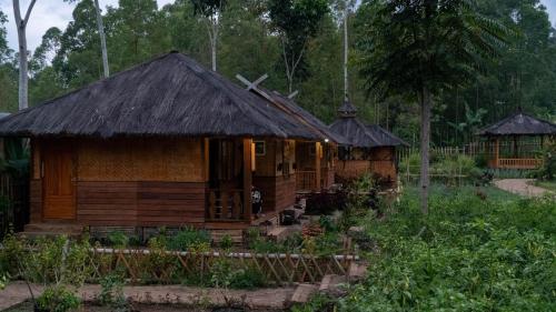 a small wooden house with a thatched roof at Kampung Bareto Cottage And Resto in Tjisurupan