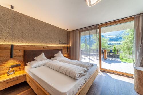 a bedroom with a large bed and a large window at Pension Sonnegg in Saltusio