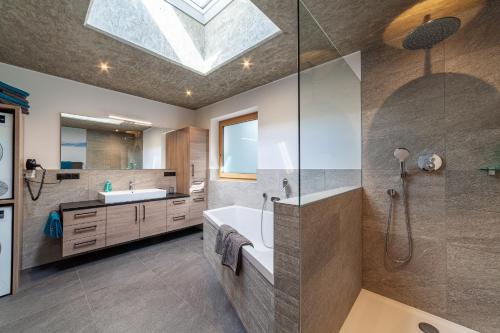 a bathroom with a sink and a shower with a skylight at Pension Sonnegg in Saltusio