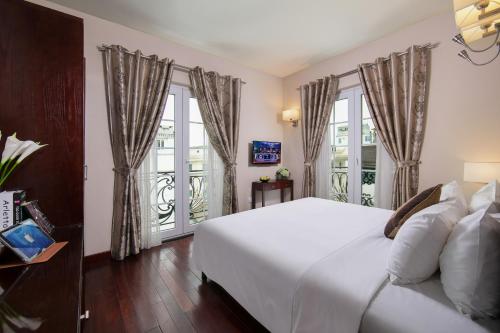 a bedroom with a white bed and two windows at Sunline Hotel in Hanoi