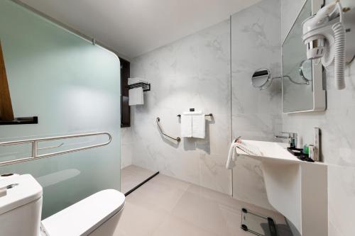 a white bathroom with a toilet and a sink at Marlo Hotel in Jeddah