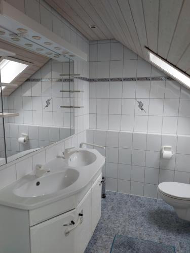 a white bathroom with two sinks and a toilet at FeWo Stauber in Amtzell