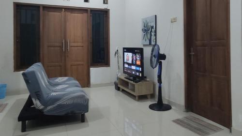 a living room with a chair and a television at Choko Homestay in Tjolomadu
