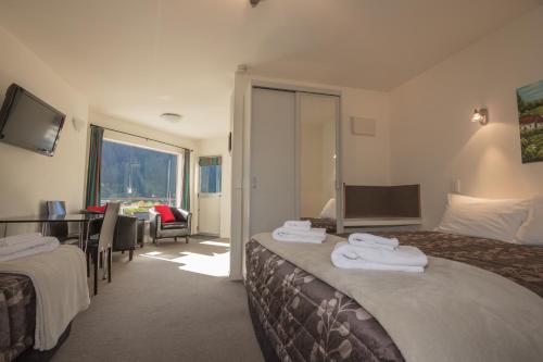 Caples Court Motel & Apartments في كوينزتاون: غرفة فندقية بسريرين وغرفة طعام