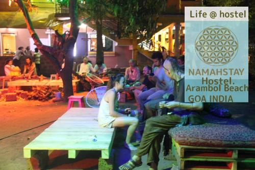 a group of people sitting on a bench next to a sign at NamahStay Hostel, Cowork & Artist residency Arambol in Arambol
