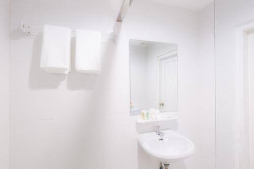 a white bathroom with a sink and a mirror at Hotel Zing Phnom Penh in Phnom Penh