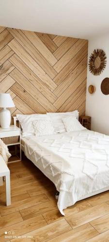 a bedroom with a white bed with a wooden wall at Boho apartament - studio in Kołobrzeg