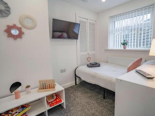 a bedroom with a bed and a tv on the wall at 3-Bed 5-6 berth modernised bungalow! in Tenby