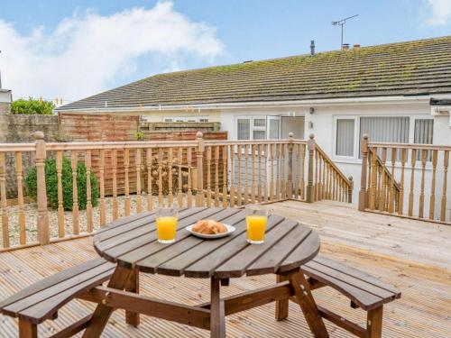 a wooden deck with a table and two glasses of orange juice at 3-Bed 5-6 berth modernised bungalow! in Tenby