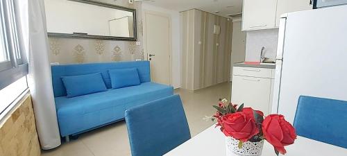 un sofá azul en una cocina con rosas sobre una mesa en Colony Beach Hotel Apartment Tel Aviv Bat Yam 36 en Bat Yam
