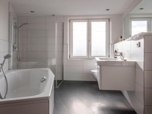 ein Badezimmer mit einer Badewanne, einem Waschbecken und einem WC in der Unterkunft Stylish Apartment in Quedlinburg with Panoramic Window in Quedlinburg