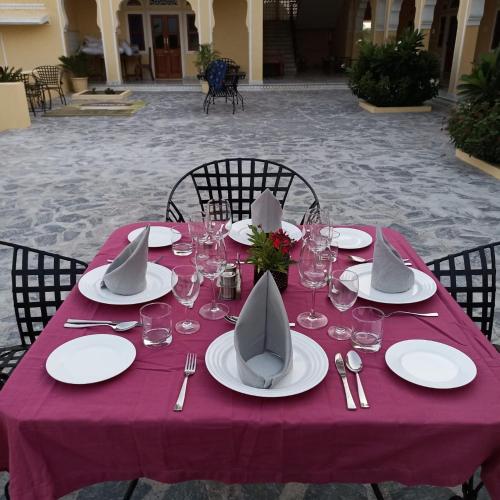 a table with a purple table cloth with plates and wine glasses at Fort Chabariya in Kekri