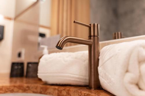 a bathroom sink with a faucet and white towels at Bad Ratzes in Siusi