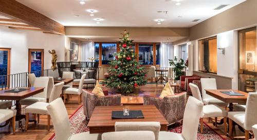 a christmas tree in a restaurant with tables and chairs at Bad Ratzes in Siusi