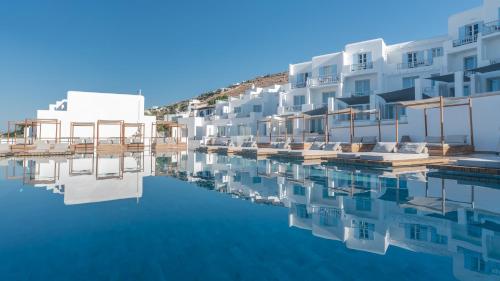 a row of white buildings next to a body of water at Manoula's Beach Mykonos Resort in Agios Ioannis Mykonos