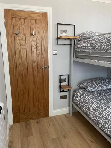 a room with two bunk beds and a wooden door at 265 Belle Aire, Modern Property in Hemsby