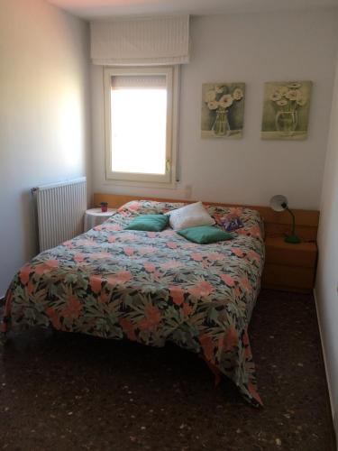 a bedroom with a bed with a comforter and a window at Primera línea aguas termales zen in Comarruga