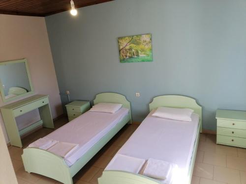 two twin beds in a room with a mirror and a dresser at KIRKOS “PORTO” in Samothraki